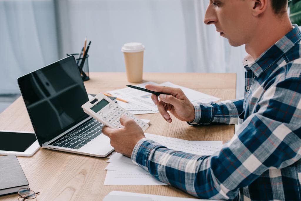 Accountant working with a calculator, documents and a laptop